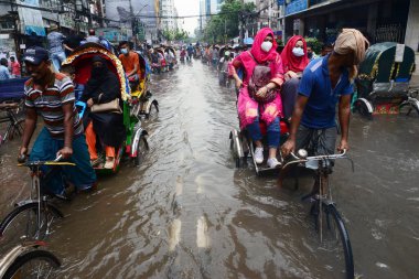 Araçlar sürmeye çalışıyor ve vatandaşlar 12 Ekim 2020 'de Bangladeş' teki Dhaka caddelerinde yürüyorlar. Şiddetli muson yağmurları Dhaka şehrinin birçok bölgesinde aşırı su kütüklerine neden oldu., 