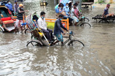 Araçlar sürmeye çalışıyor ve vatandaşlar 14 Ekim 2020 'de Bangladeş' teki Dhaka caddelerinde yürüyorlar. Şiddetli muson yağmurları Bangladeş 'in Dhaka şehrinin birçok bölgesinde aşırı su kütüklerine neden oldu. Yolculuk yaparken yollar sular altındaydı. 