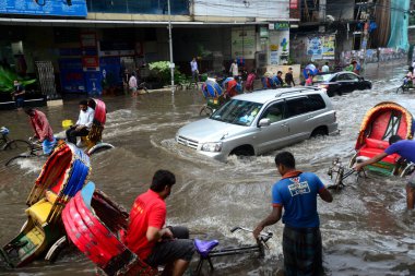 Araçlar sürmeye çalışıyor ve vatandaşlar 14 Ekim 2020 'de Bangladeş' teki Dhaka caddelerinde yürüyorlar. Şiddetli muson yağmurları Bangladeş 'in Dhaka şehrinin birçok bölgesinde aşırı su kütüklerine neden oldu. Yolculuk yaparken yollar sular altındaydı. 