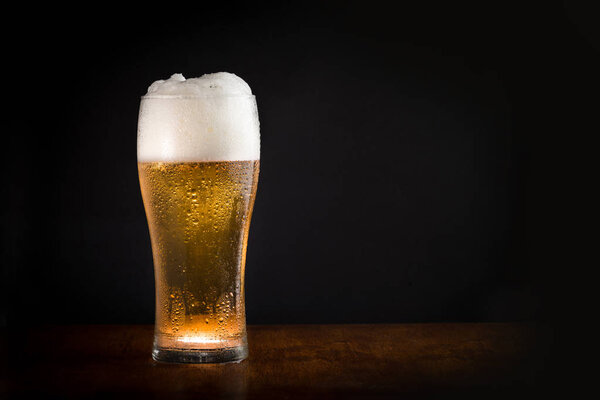Glass of fresh cold chilled beer with black background