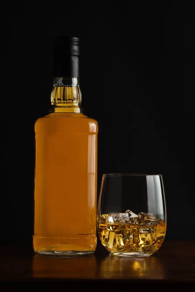 Glass of clod whiskey with a bottle of whiskey