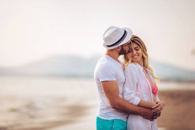 Eğleniyor kumsalda gün batımında romantik genç çift