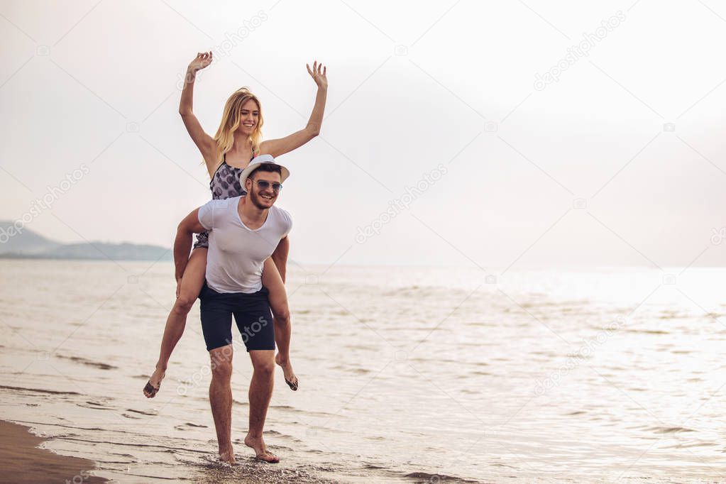 Young woman piggybacking on young boyfriend on beach