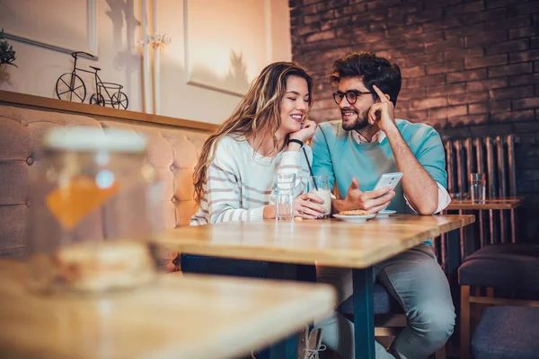 年轻夫妇坐在咖啡馆喝咖啡和使用智能手机 — 图库照片