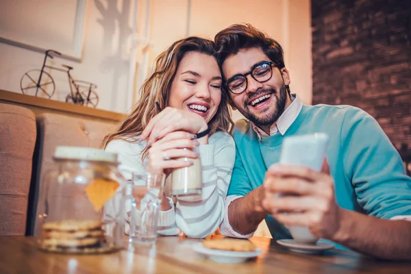 年轻夫妇坐在咖啡馆喝咖啡和使用智能手机 — 图库照片