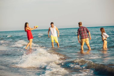 Rahatlatıcı ve having fun kumsalda genç arkadaş grubu