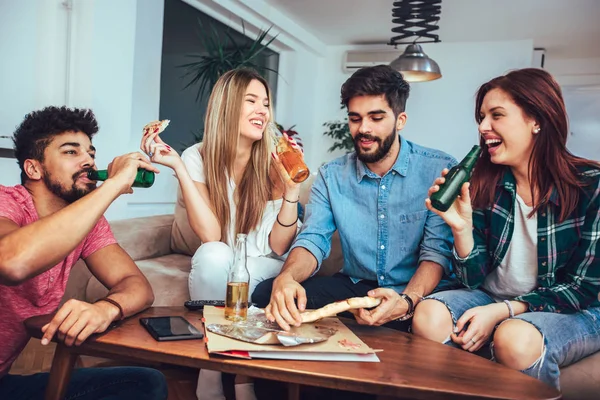 Pizza yemek, bira içme ve evde tv izlerken genç arkadaş grubu.