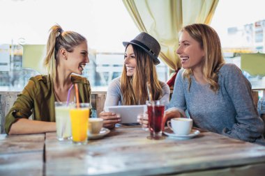Cafe sohbet keyfi ve dijital tablet kullanarak arkadaşlar.