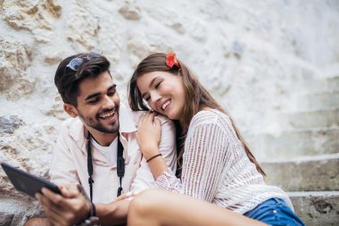 Merdivenlerde oturan ve tablet bilgisayar başında arıyor Romantik Çift