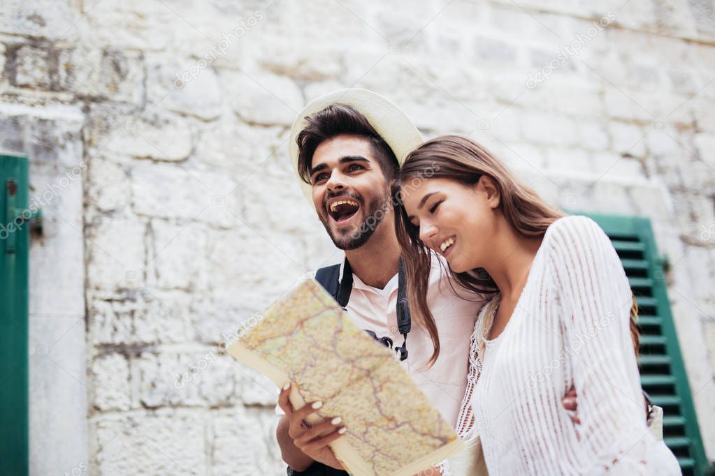 Traveling couple of tourists walking around old town with map and camera.