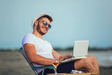 Bilgisayar ile plajda çalışan adam. Bağımsız çalışma