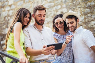 Genç turist arkadaşlar eğlenmeye dijital tablet ile Grup