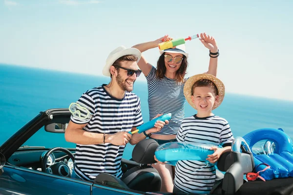 Happy family travel by car to the sea. People having fun in cabriolet. Summer vacation concept