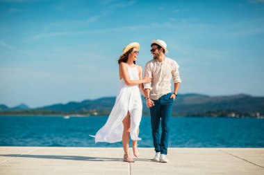 Genç gülümseyen iki yürüyor ve sahil üzerinde gülüyor