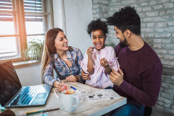 Mom and dad drawing with their daughter. Girl and mixed race parents having fun at home.