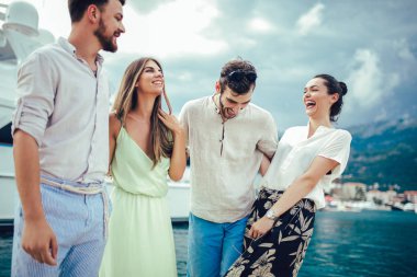 Bir turistik deniz tatil tekne ile liman tarafından arka planda yürüyen arkadaşlar