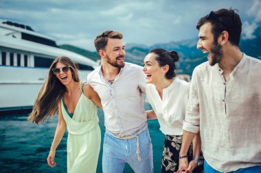 Bir turistik deniz tatil tekne ile liman tarafından arka planda yürüyen arkadaşlar