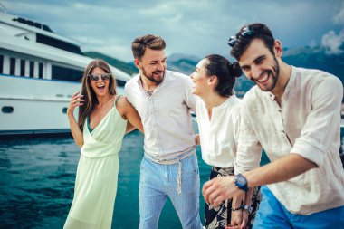 Bir turistik deniz tatil tekne ile liman tarafından arka planda yürüyen arkadaşlar