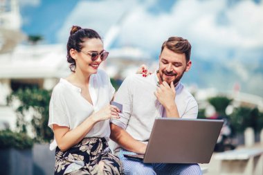 Güzel romantik çift dizüstü bilgisayar kullanarak. Belgili tanımlık laptop resimleri, arka plan üzerinde tekne ile turistik deniz tatil liman tarafından seyahat ederken izlerken.