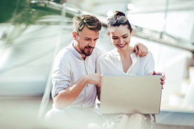 Güzel romantik çift dizüstü bilgisayar kullanarak. Belgili tanımlık laptop resimleri, arka plan üzerinde tekne ile turistik deniz tatil liman tarafından seyahat ederken izlerken.