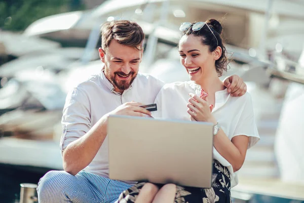 Güzel romantik çift dizüstü bilgisayar kullanarak. Belgili tanımlık laptop resimleri, arka plan üzerinde tekne ile turistik deniz tatil liman tarafından seyahat ederken izlerken.