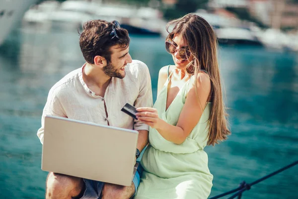 Güzel romantik çift dizüstü bilgisayar kullanarak. Belgili tanımlık laptop resimleri, arka plan üzerinde tekne ile turistik deniz tatil liman tarafından seyahat ederken izlerken.