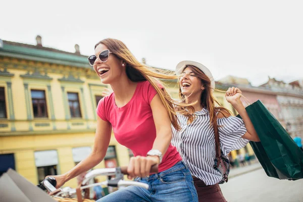 两个金发美女骑着自行车在城市购物 — 图库照片