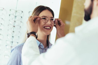 Optik merkezi müşteri için görsel muayene yaparken göz doktoru.