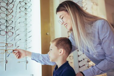 Anne ve oğlu optik dükkanında gözlük seçiyor..