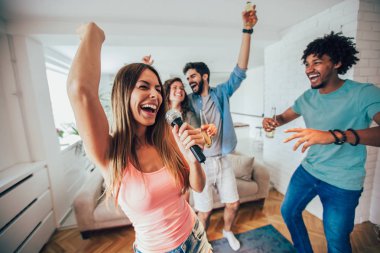 Evde karaoke oynayan genç mutlu arkadaş grubu. 