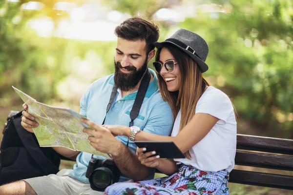 快乐的旅游情侣看着地图在公园的长凳上晴朗的一天 — 图库照片