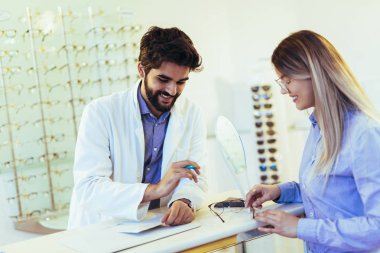 Göz doktoru yardımı ile optik mağazasından yeni gözlük seçiminde kadın 