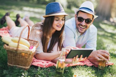 Çift üzerinde dijital tablet kullanarak park piknik battaniyeye yalan