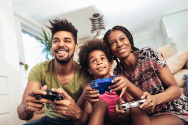 Aile birlikte video oyunları oynarken kanepede oturan gülümseyen