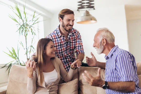 Young couple talking with their senior father at home