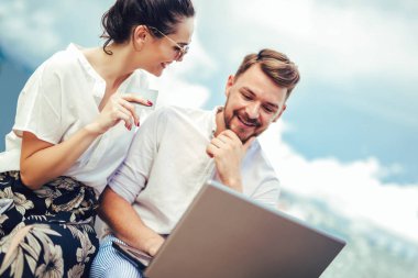 Arka plan üzerinde tekne ile turistik deniz tatil liman tarafından laptop ve kredi kartı kullanarak güzel romantik çift
