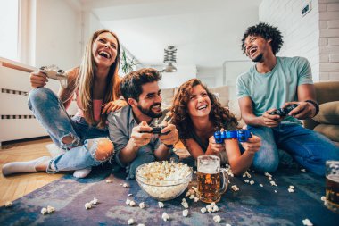 Bir grup arkadaş evde video oyunu oynuyor, eğleniyorlar..