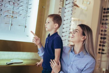 Anne ve oğlu optik dükkanında gözlük seçiyor..