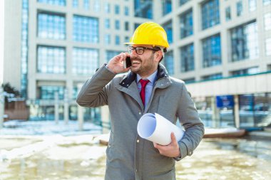 Koruyucu kask ofis binası önünde durarak telefon konuşma içinde mimar