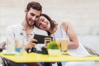 Genç çift kahve içme ve kafede otururken tablet kullanarak turist