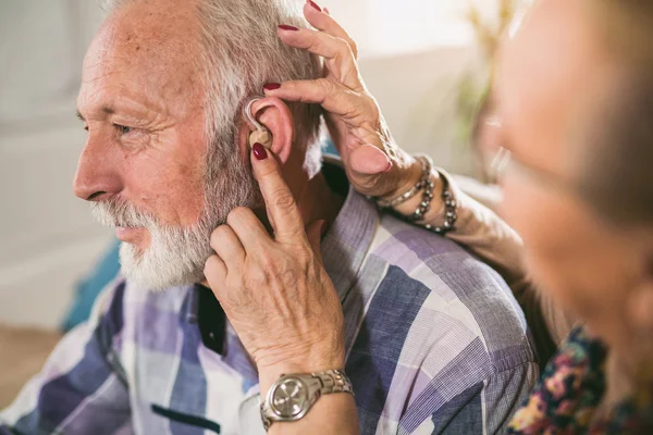 woman wearing hearing aid on male ear, close-up, hearing problem concept