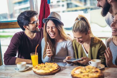 Pizzacı masada otururken tadını genç arkadaşlar 