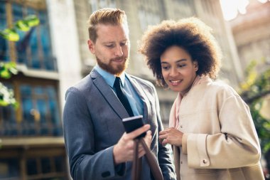 Açık havada Smartphone kullanarak mutlu iş çift 