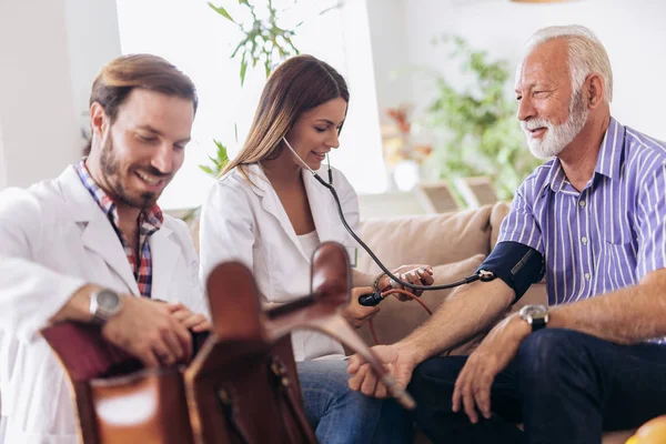 Pielęgniarka Pomiar Ciśnienia Krwi Starszy Człowiek Domu Uśmiechając Się Siebie — Zdjęcie stockowe