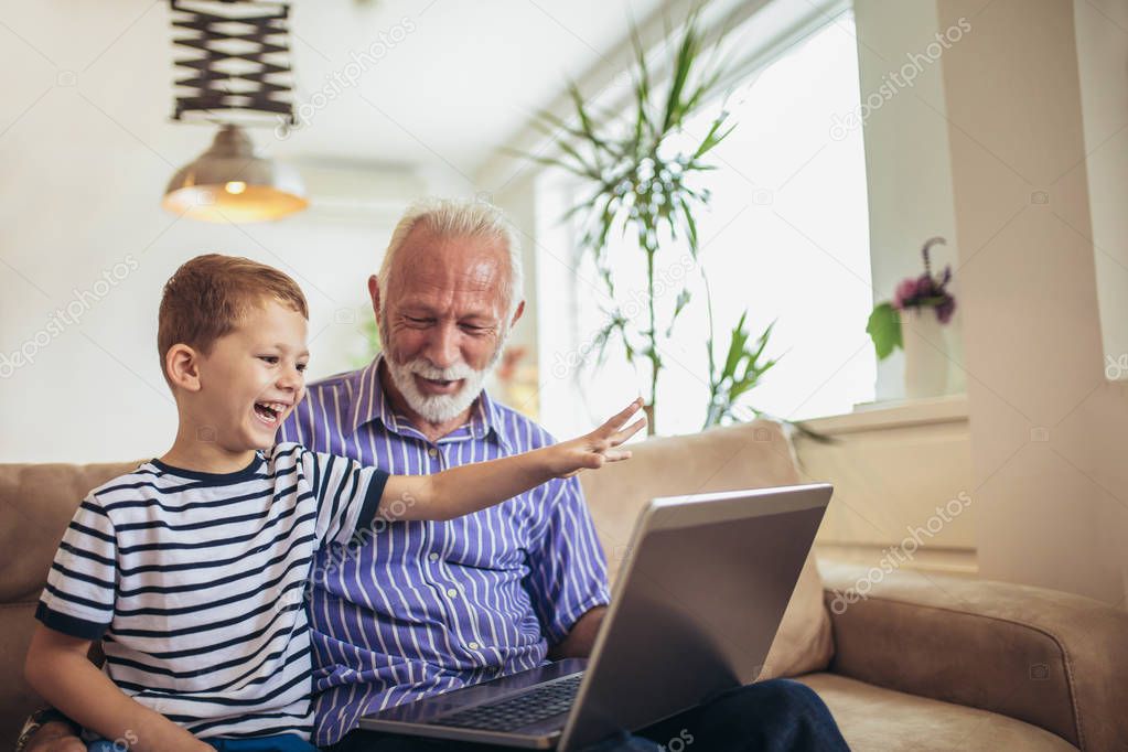 Grandfather and grandson using laptop together