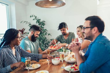Grup mutlu genç arkadaşlar evde akşam yemeği zevk. Akşam yemeği tadını çok ırklı arkadaş grubu