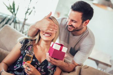 gülümseyen genç adam şaşırtıcı neşeli kadın evde hediye kutusu