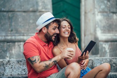Oturan merdiven ve kahve içme, dijital tablet kullanarak üzerinde romantik turist Çift.