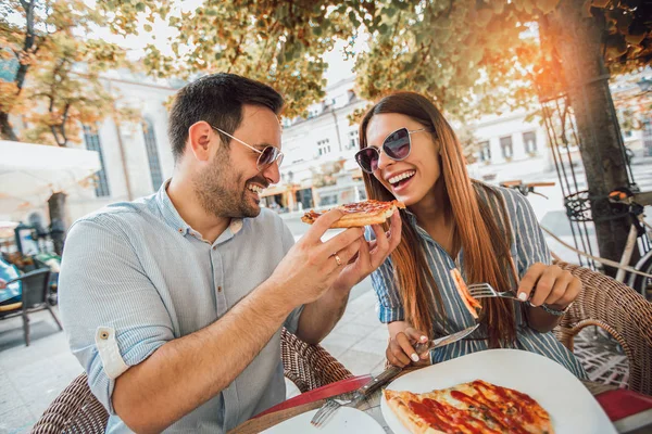 Couple eating pizza snack outdoors.They are sharing pizza and eating.