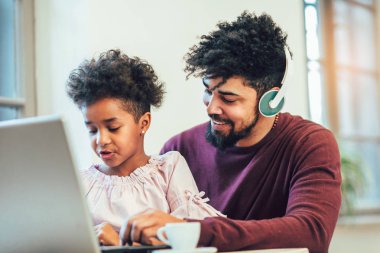 Genç Afro-Amerikan baba kızı ile birlikte siting, bir dizüstü bilgisayar kullanıyorsanız.